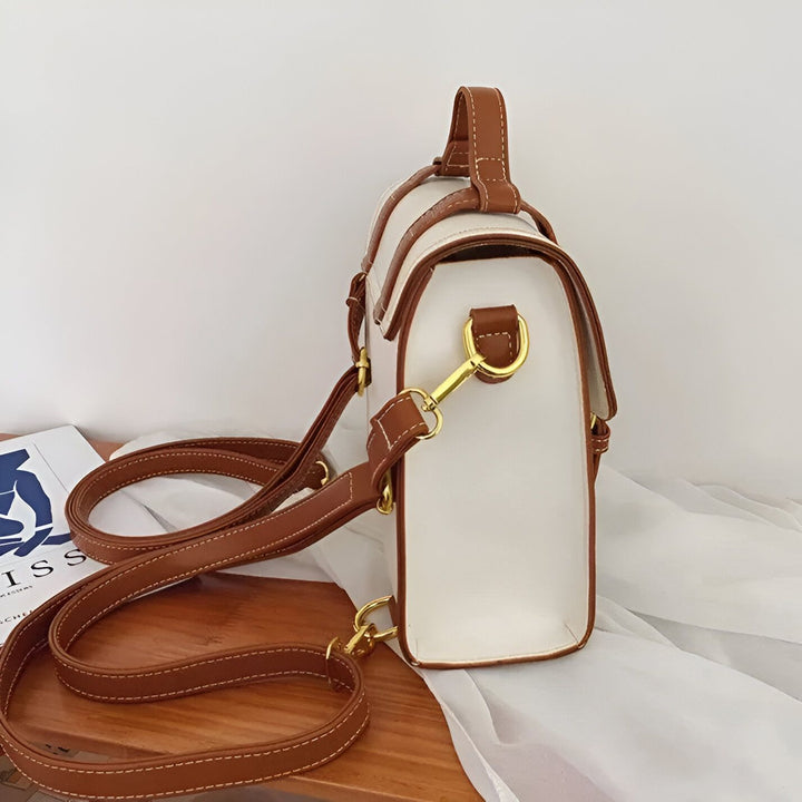 Sac blanc avec sangles marron et boucles dorées sur une table en bois., 46193899569376,46193899602144,46193899634912