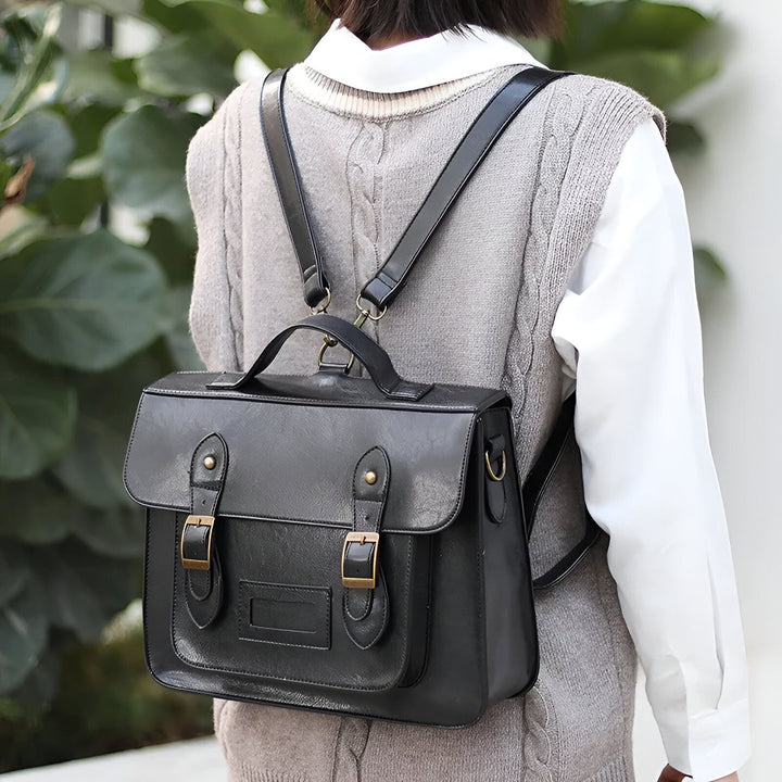 Sac à dos cartable en cuir noir porté par une personne avec un gilet gris et une chemise blanche., 46193905008864,46193905041632