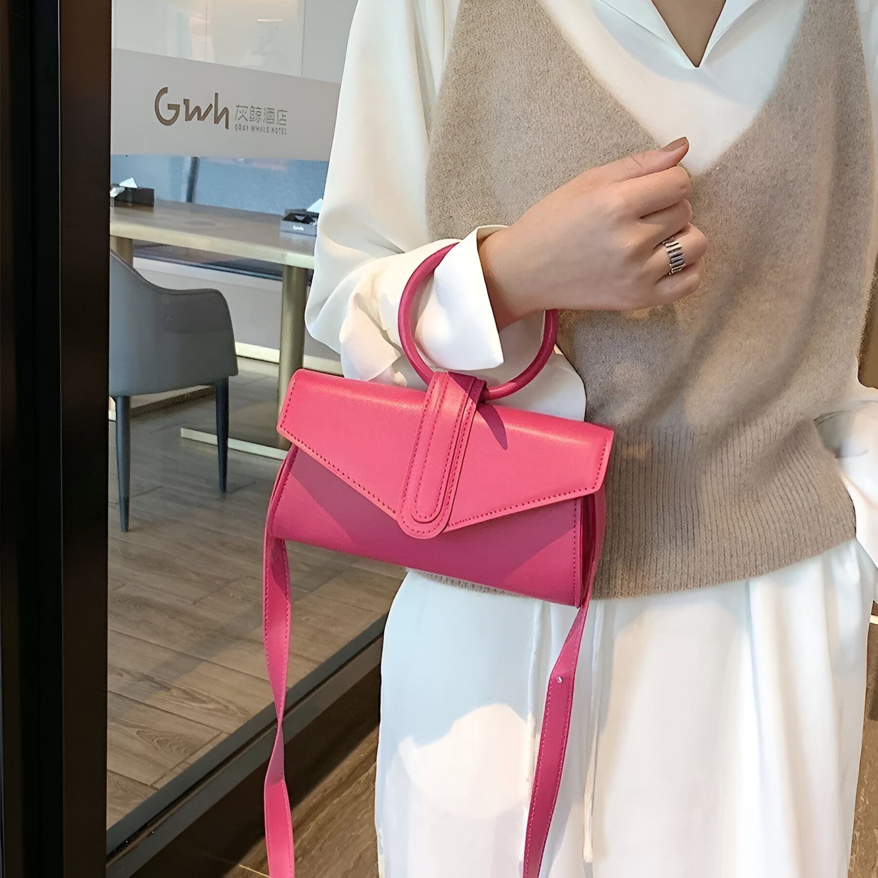 Une femme portant un sac à main rose avec une poignée ronde.