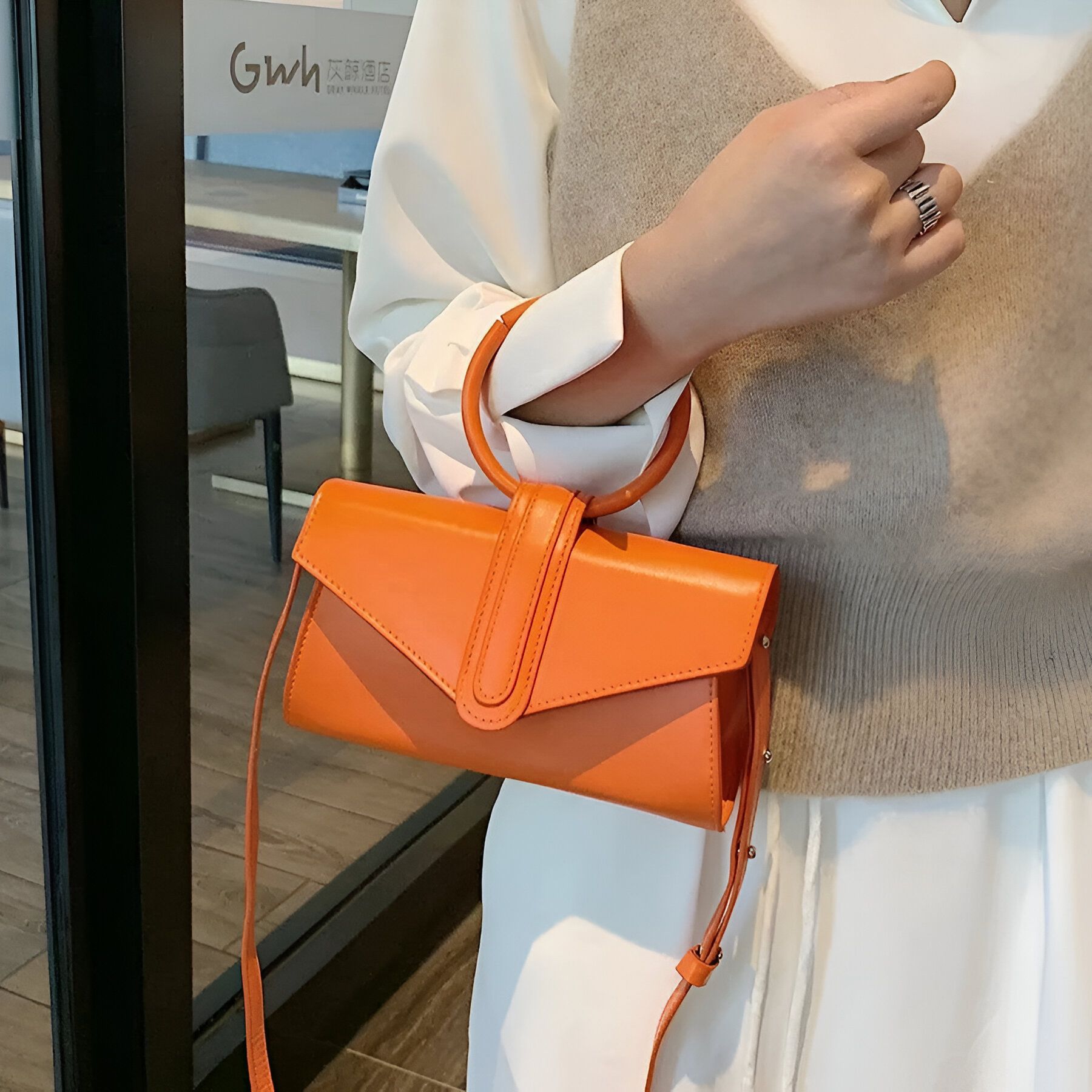 Un sac à main orange à anse ronde porté par une femme.