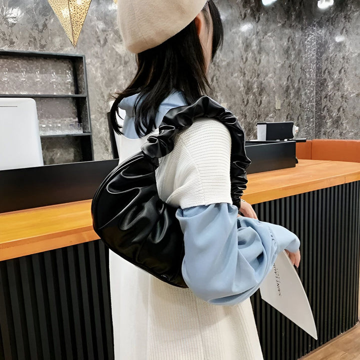 Personne portant un béret beige et un sac croissant noir à anse froncée sur l'épaule., 46193963401440,46193963434208,46193963466976,46193963499744,46193963532512