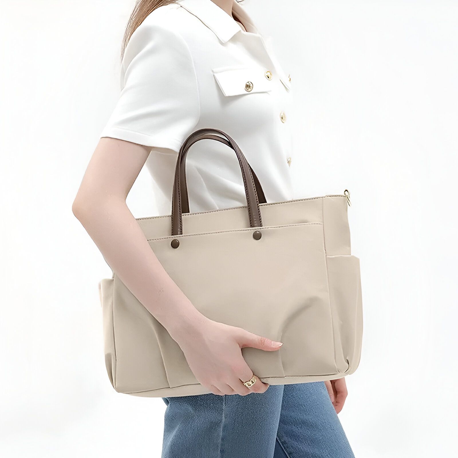 Une femme portant un sac à main beige avec des anses marron.