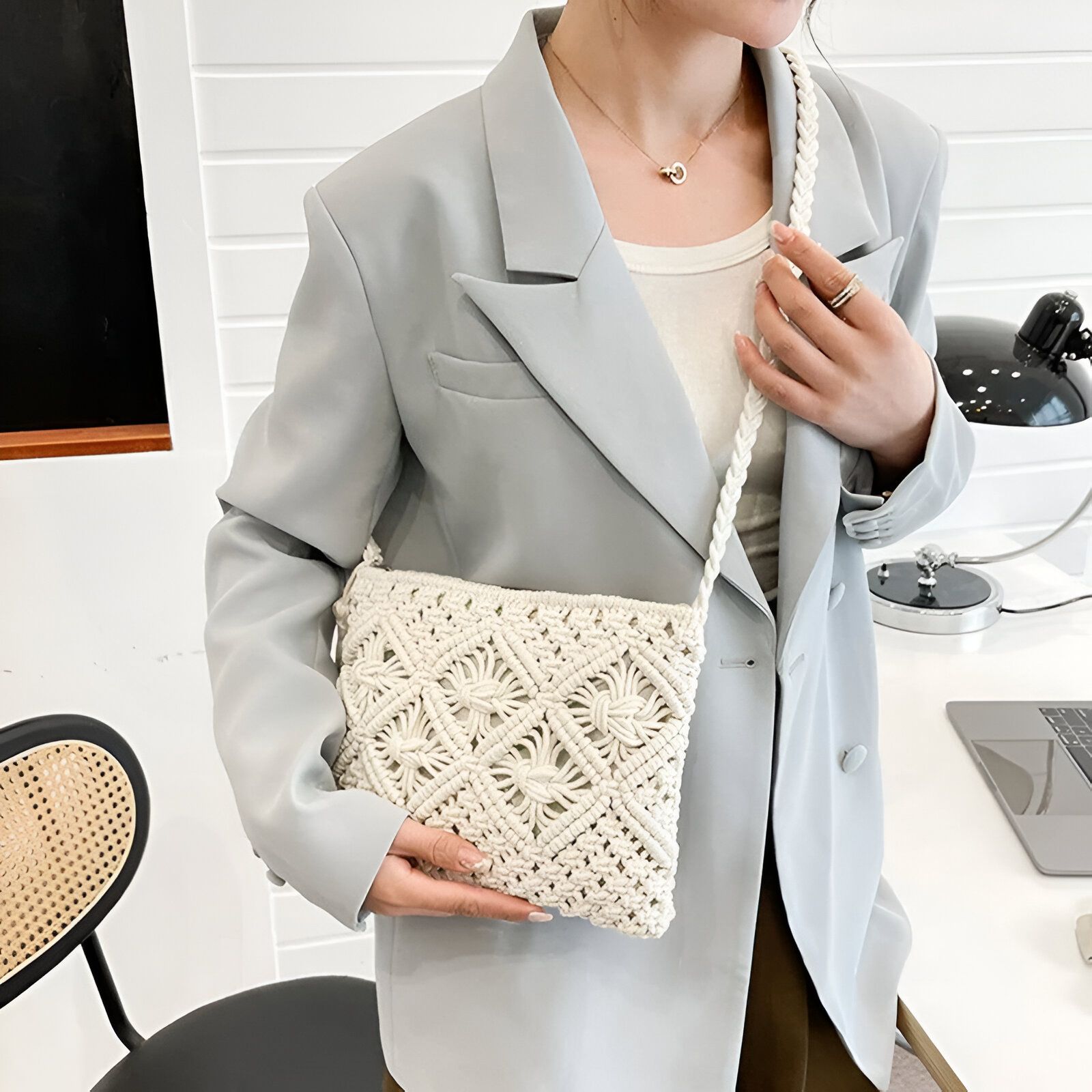 Une femme portant un blazer bleu clair et un sac à main en macramé blanc.