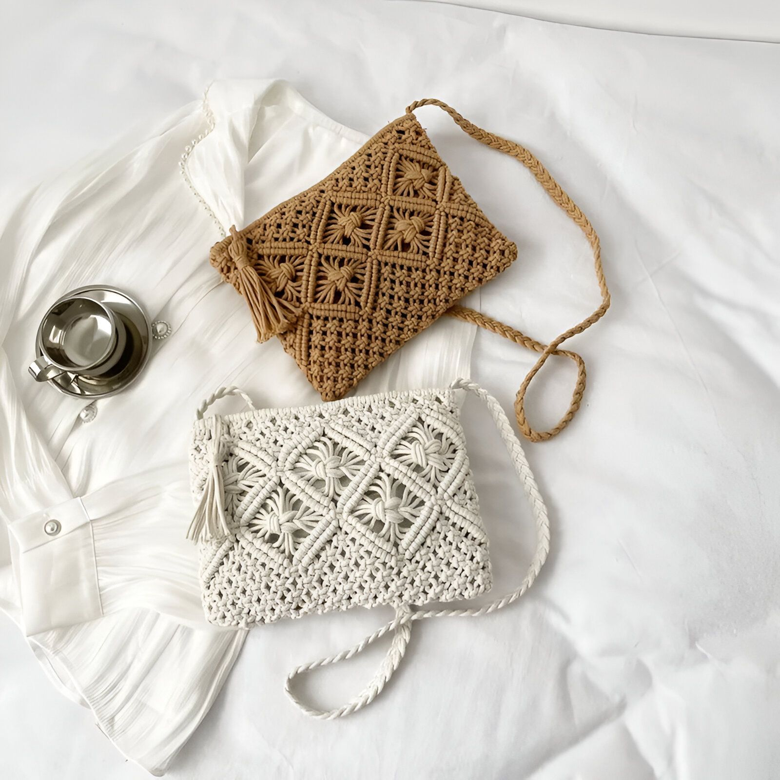 Deux petits sacs à main en macramé, l'un beige et l'autre blanc, posés sur un lit blanc.