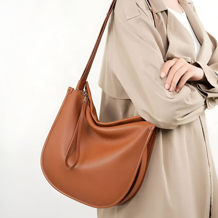 Sac à main marron en cuir porté à l'épaule par une personne en manteau beige, 46193857102048,46193857167584,46193857200352,46193857233120