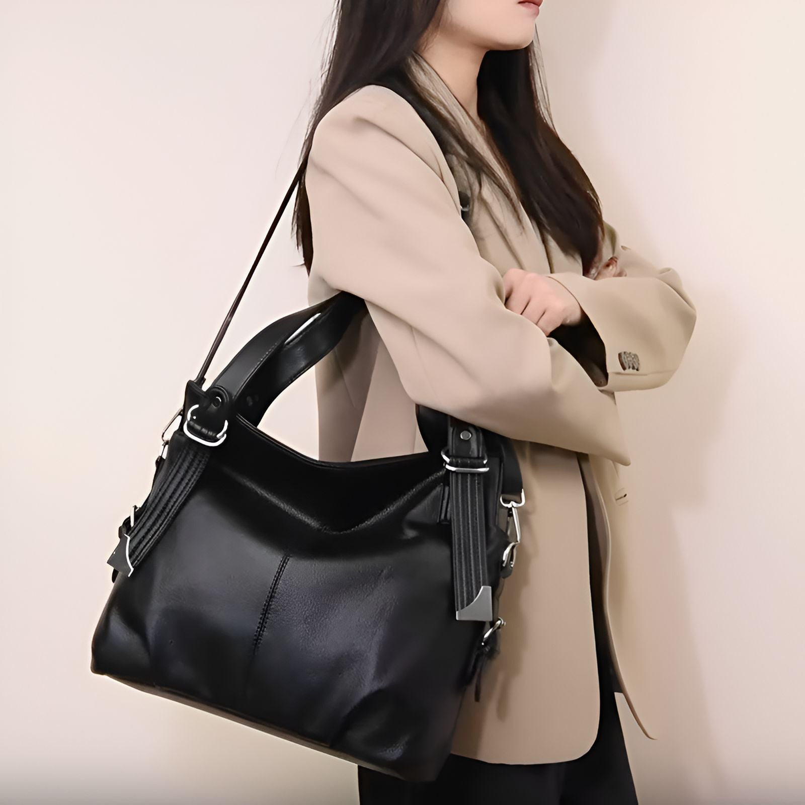 Une femme porte un sac à main noir en cuir avec une bandoulière.