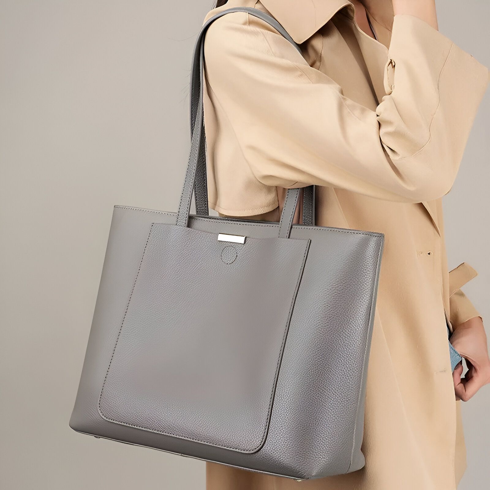 Une femme portant un grand sac à main gris en cuir.