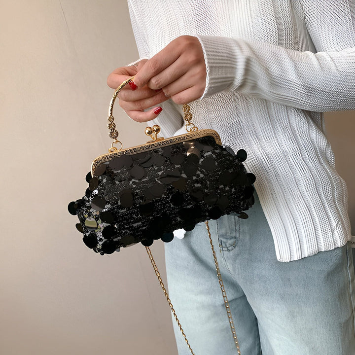 Pochette à main noire à sequins avec poignée et chaîne dorées tenue par une personne., 46194028478688,46194028511456