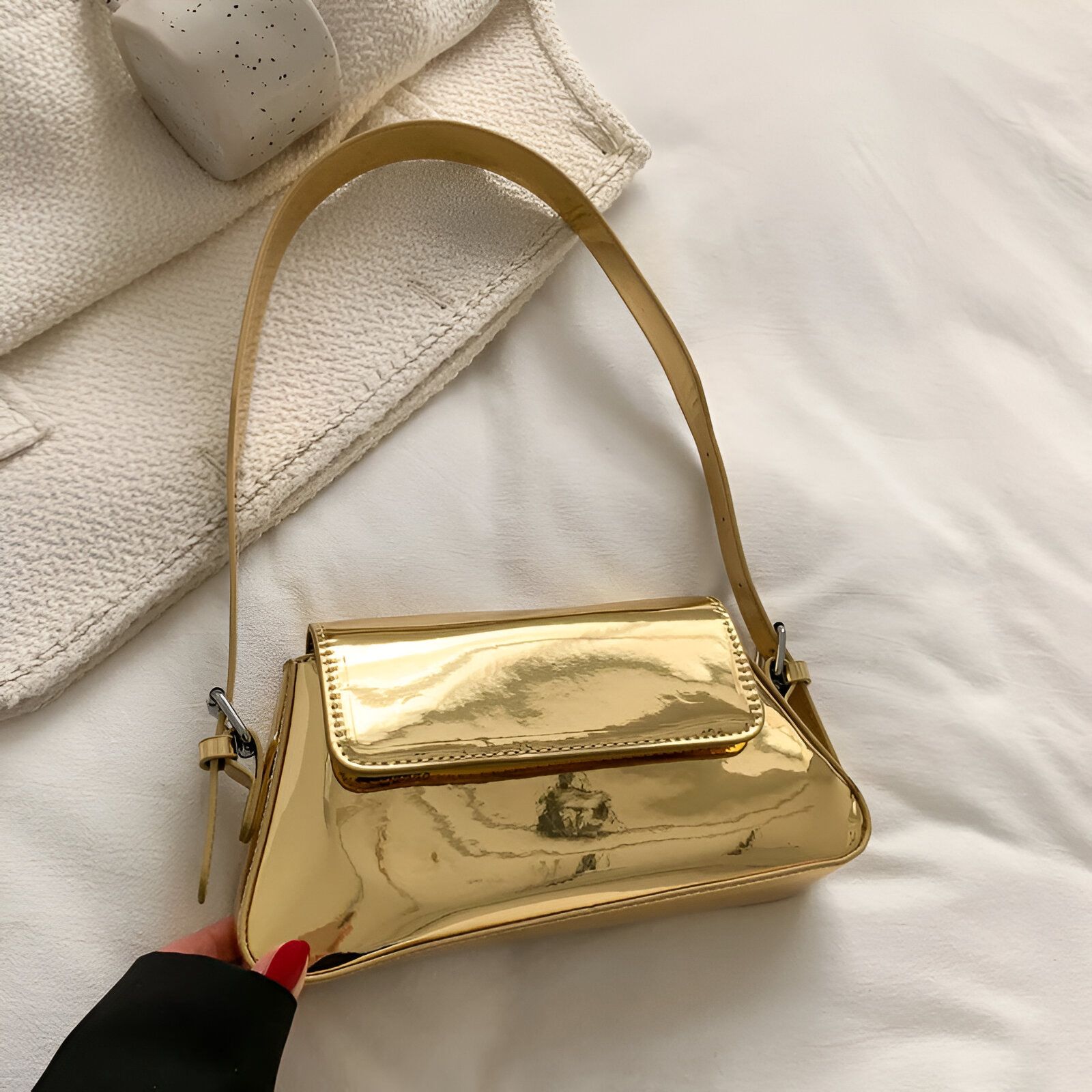 Un sac à main doré brillant avec une bandoulière.