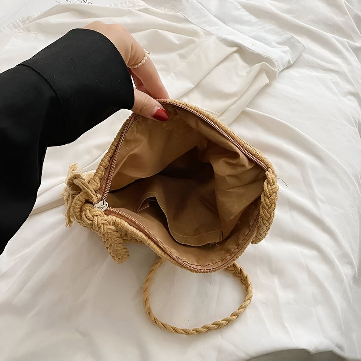 Une main tient ouvert un petit sac en paille tressée beige avec fermeture éclair, doublure et anse tressée., 46193947640032,46193947672800,46193947705568