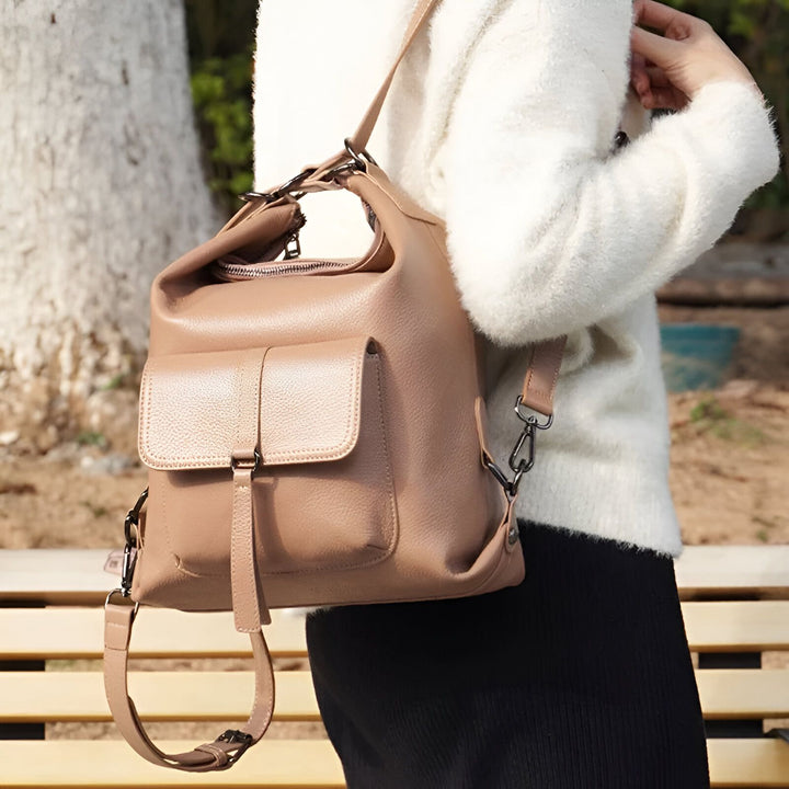 Sac à dos en cuir taupe avec grande poche frontale porté sur l'épaule par une personne., 46193840029920,46193840062688,46193840095456,46193840128224,46193840160992