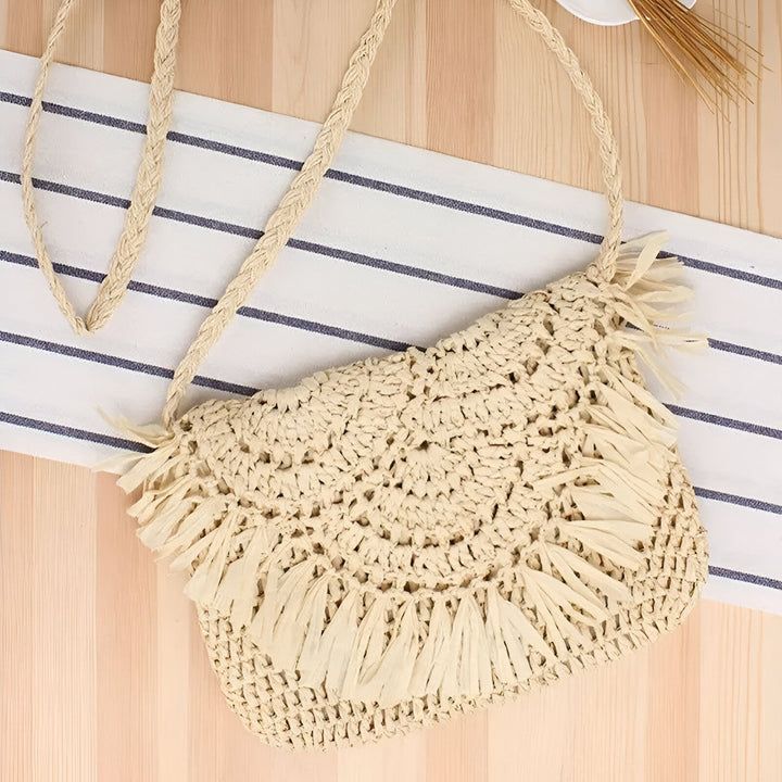 Sac à bandoulière tressé en paille beige avec franges sur fond bois et tissu., 46193921884384,46193921917152