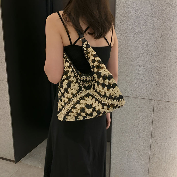 Femme avec robe noire et sac crochet noir et beige porté épaule., 46193948721376,46193948754144