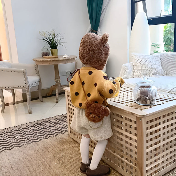 Enfant de dos avec pull jaune à pois, short beige, bonnet ours et sac ours., 46193981587680,46193981620448