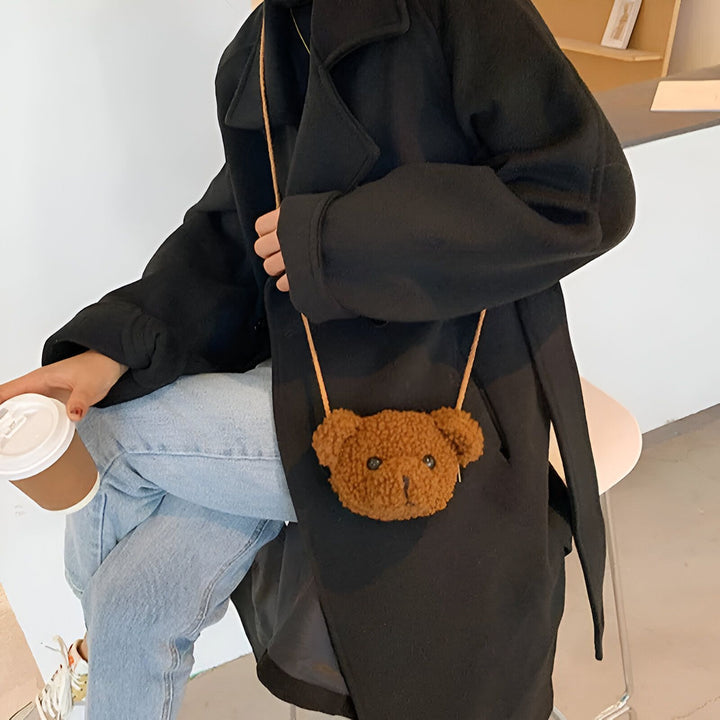 Personne en manteau noir avec un petit sac marron en forme de tête d'ours en peluche., 46193981587680,46193981620448