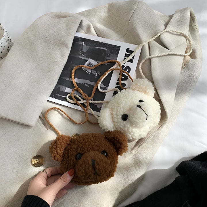 Deux sacs en forme de tête d'ours pelucheux, brun et blanc, posés sur un manteau beige., 46193981587680,46193981620448