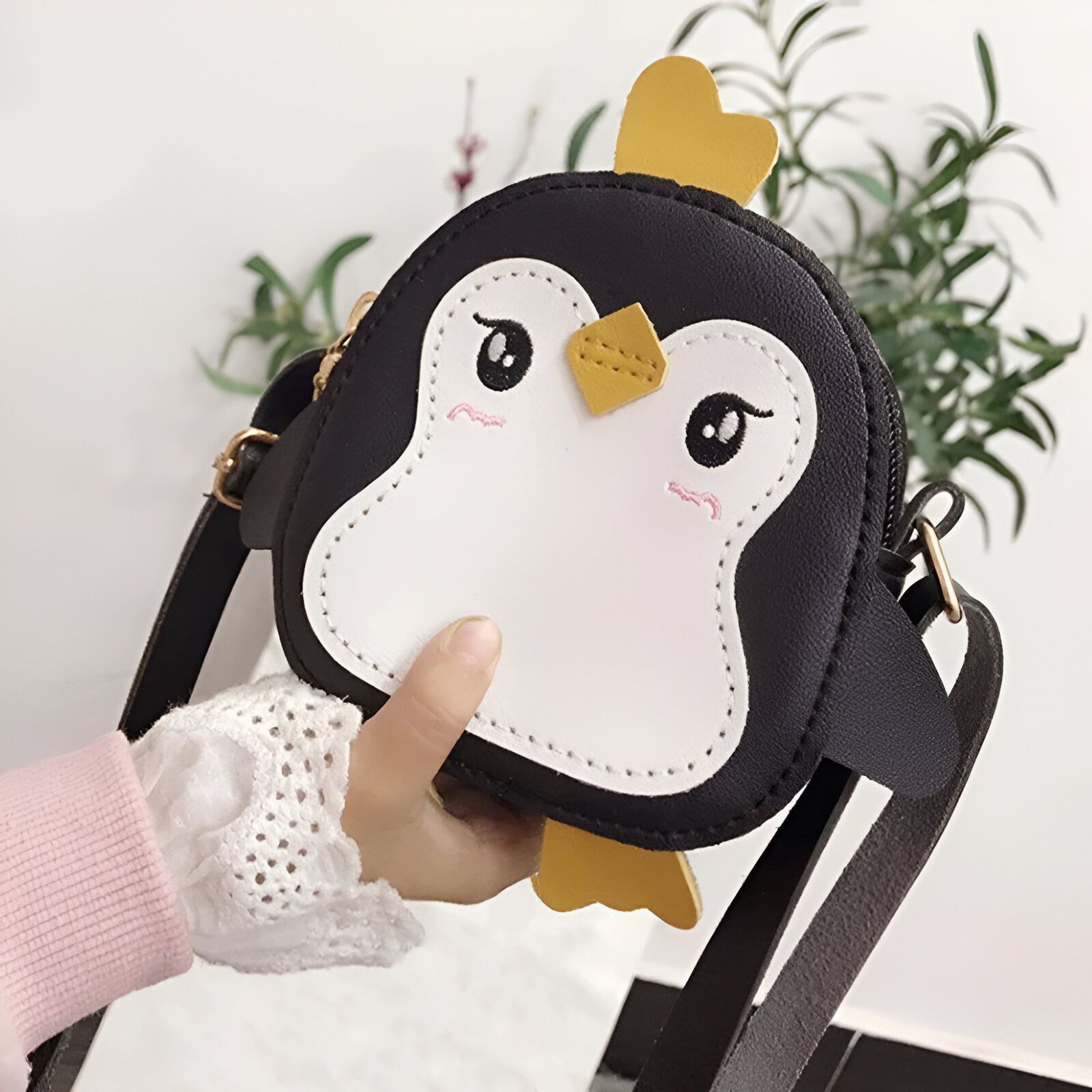 Petit sac à main en forme de pingouin noir et blanc avec une lanière noire.