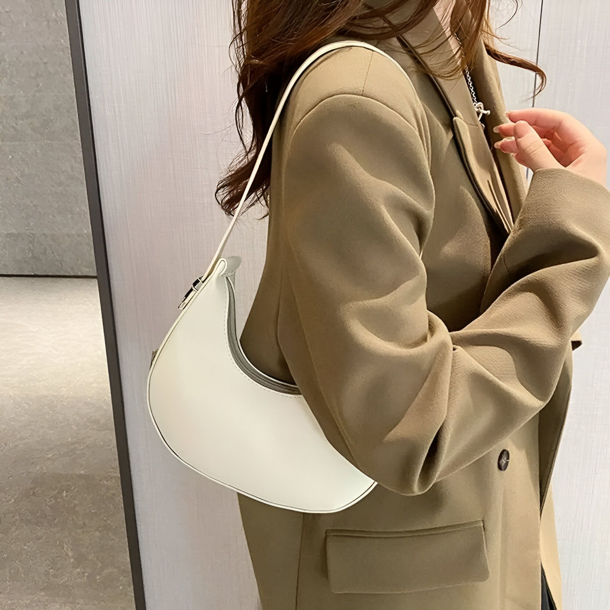 Une femme portant un blazer beige avec un sac à main blanc en forme de croissant de lune.