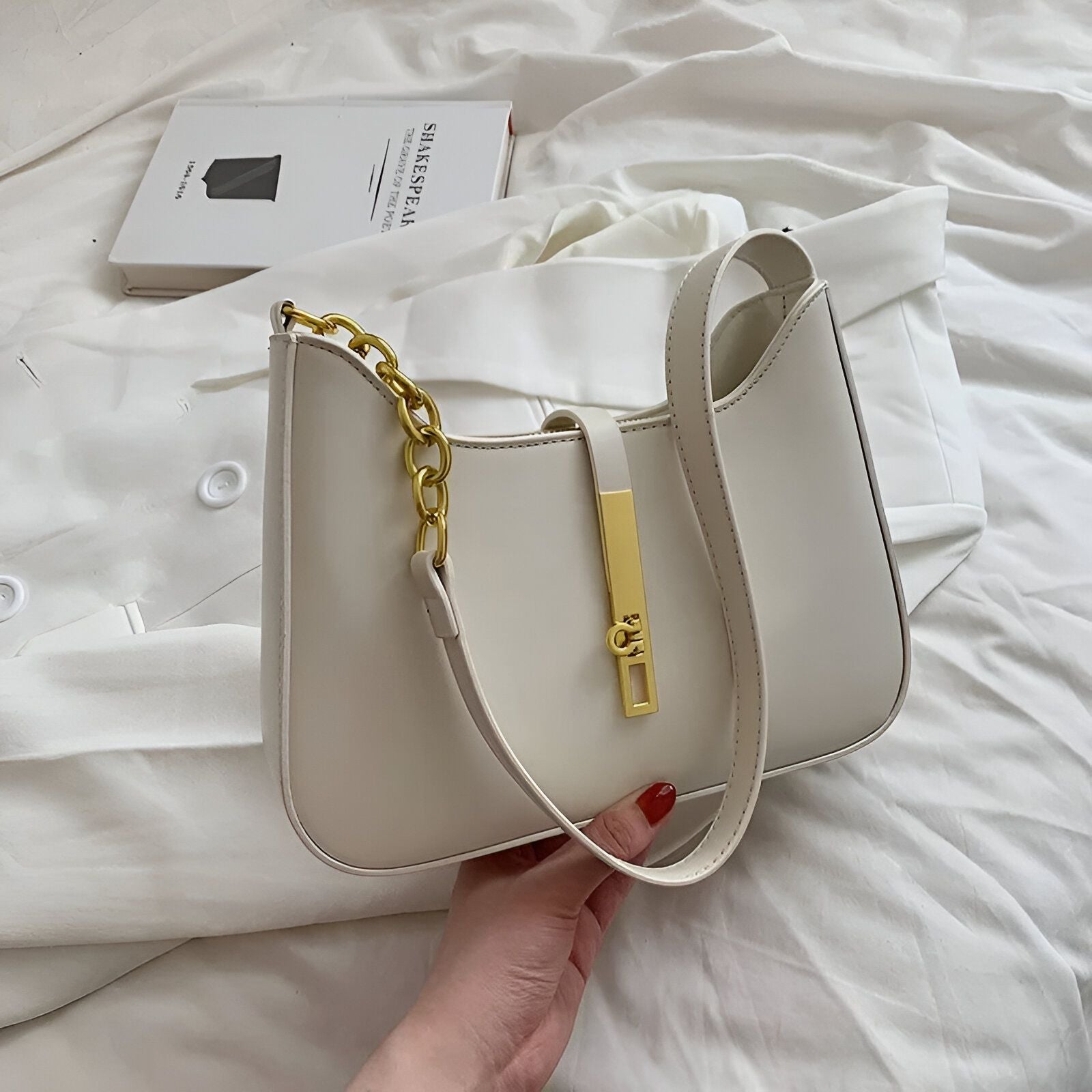 Un sac à main blanc avec une chaîne dorée et une fermeture dorée.