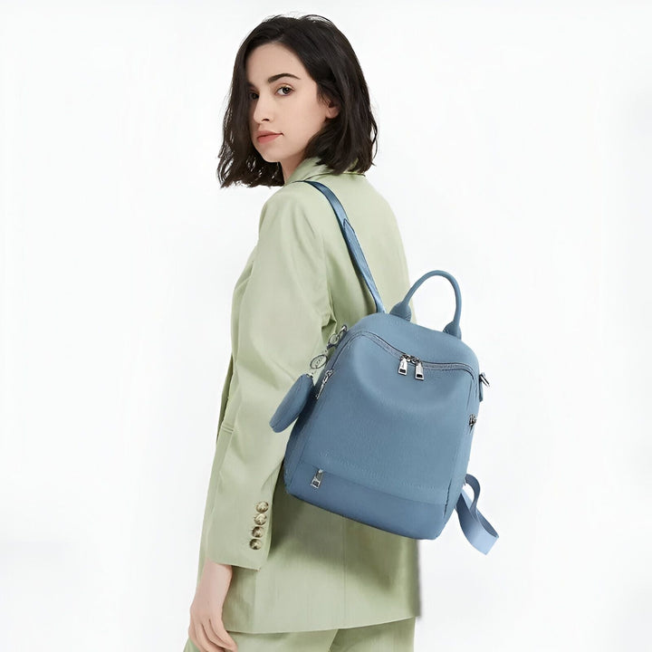 Femme en costume vert clair portant un sac à dos bleu sur l'épaule., 46193848680672,46193848713440,46193848746208,46193848778976,46193848811744,46193848844512
