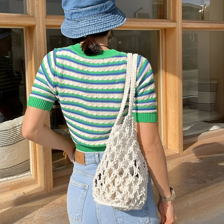 Femme de dos portant un crop top rayé vert, bleu, blanc, un bob en jean et un sac filet blanc., 46193948557536,46193948590304