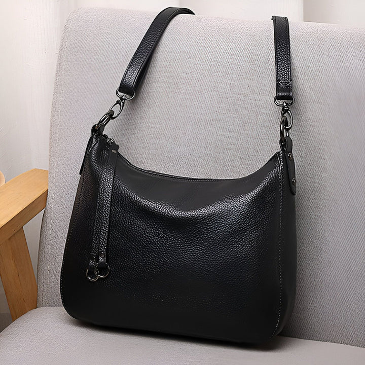 Sac à bandoulière en cuir noir sur une chaise grise., 46193845993696,46193846026464,46193846059232,46193846092000,46193846124768