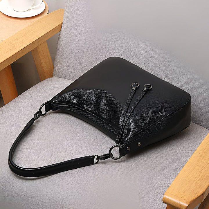 Sac à main noir en cuir posé sur une chaise., 46193845993696,46193846026464,46193846059232,46193846092000,46193846124768