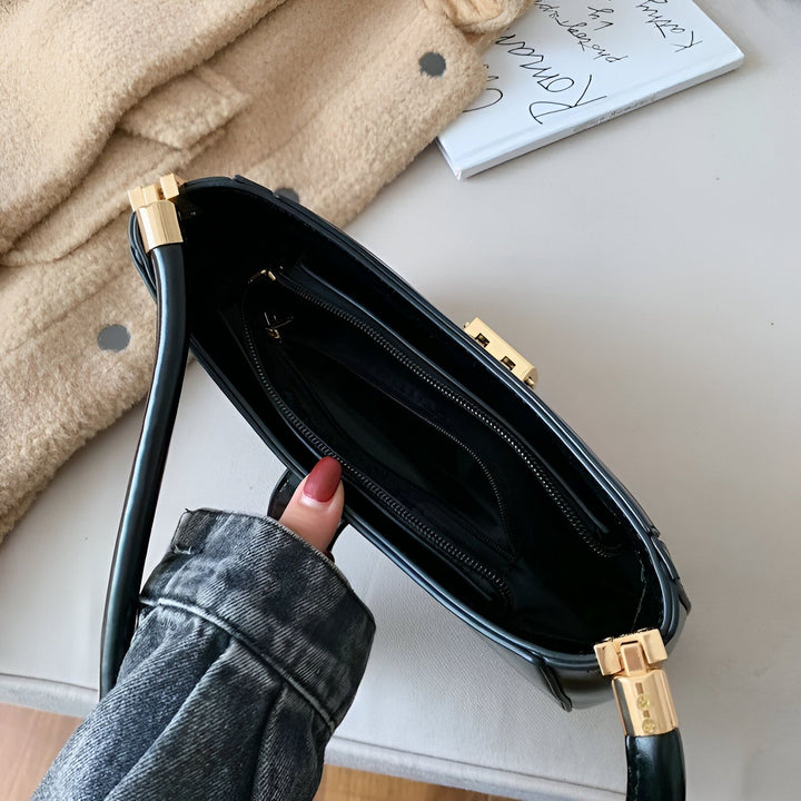 Sac à main noir ouvert avec doublure et détails dorés, tenu par une main., 46193936236768,46193936269536,46193936302304,46193936335072