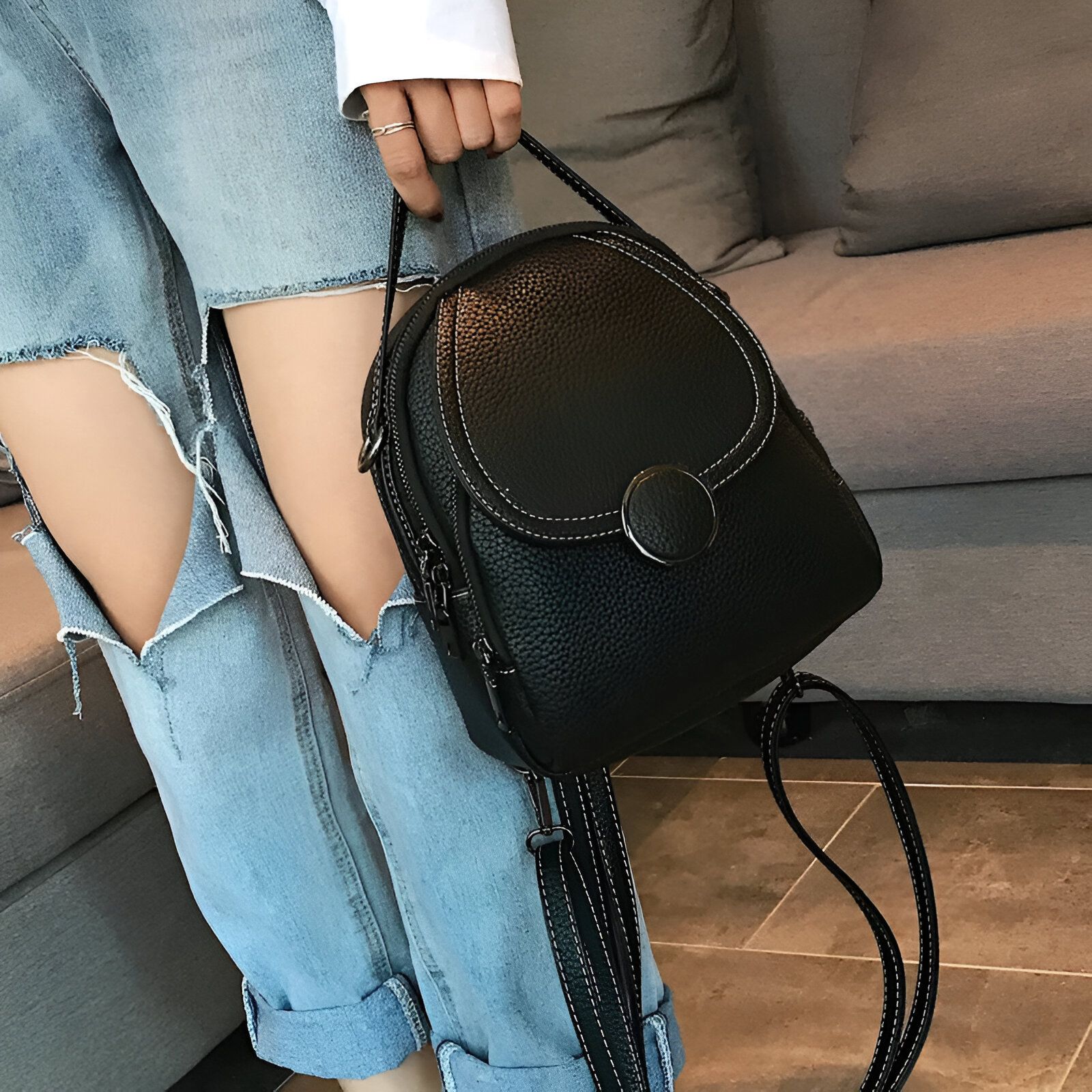 Un sac à dos noir en cuir porté par une femme en jean.