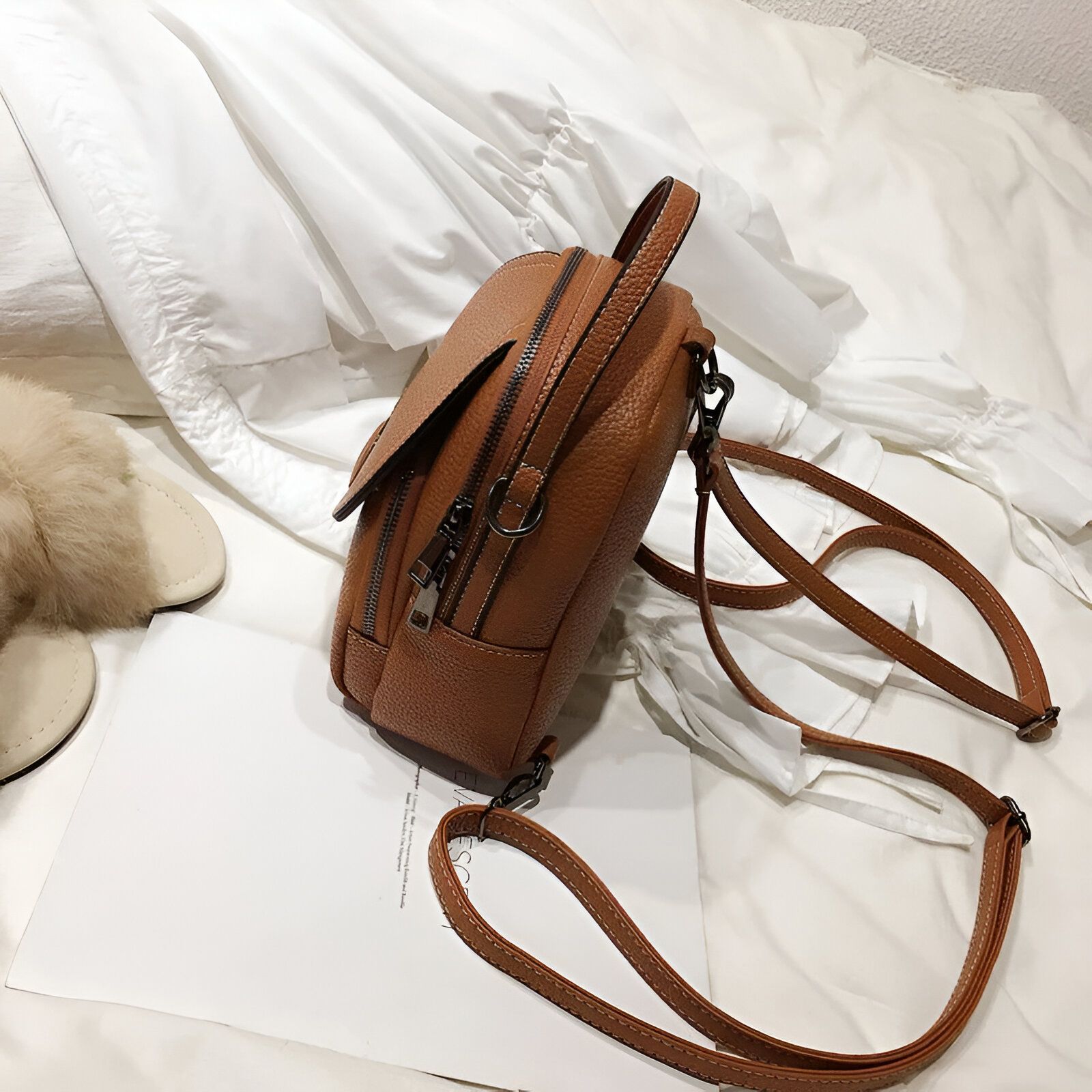 Un sac à dos brun en cuir synthétique avec une fermeture éclair.