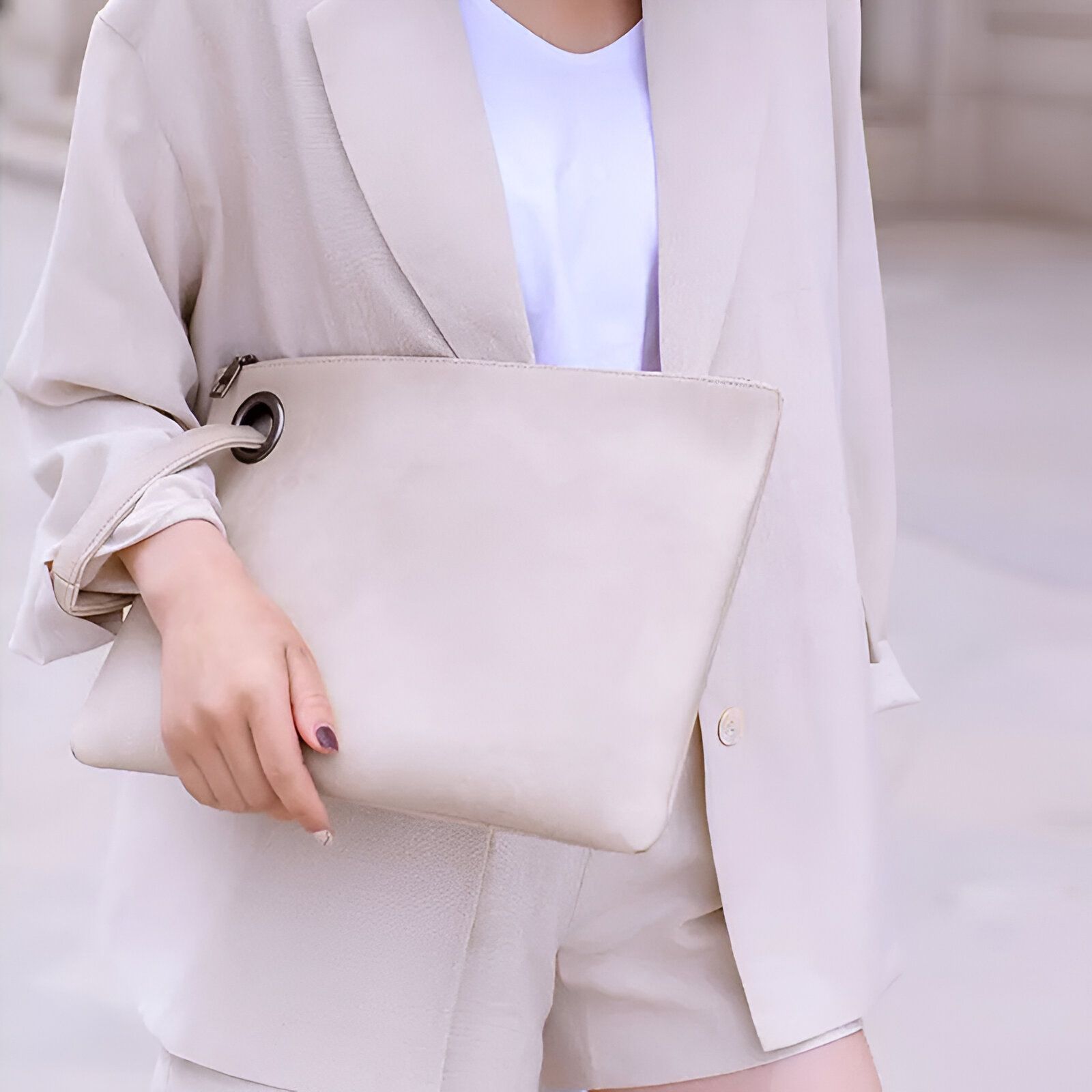 Une femme portant un blazer beige et un sac à main beige.