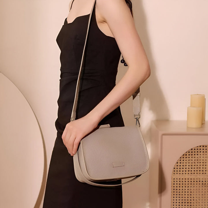 Femme en robe noire portant un sac bandoulière en cuir gris clair., 46193851039968,46193851072736