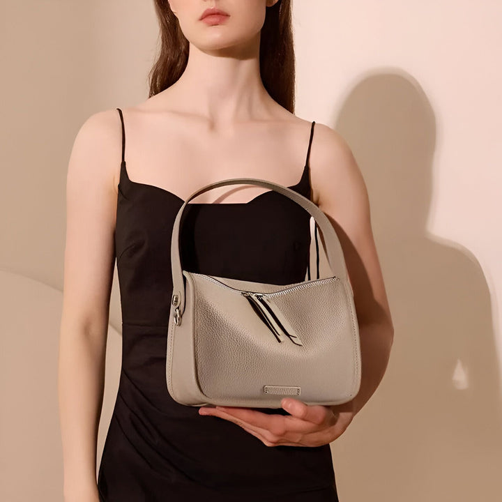 Sac à main gris en cuir grainé, tenu par une femme en robe noire., 46193851039968,46193851072736