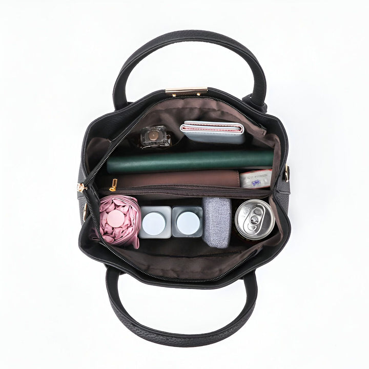 Intérieur d'un sac noir ouvert avec portefeuille, carnet vert, parapluie rose, bouteilles et canette., 46194059018464,46194059051232,46194059084000,46194059116768,46194059149536