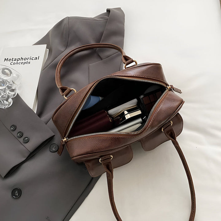 Sac à main en cuir marron ouvert montrant portefeuille, maquillage et autres objets sur un veston gris., 46193871290592,46193871323360,46193871356128,46193871388896