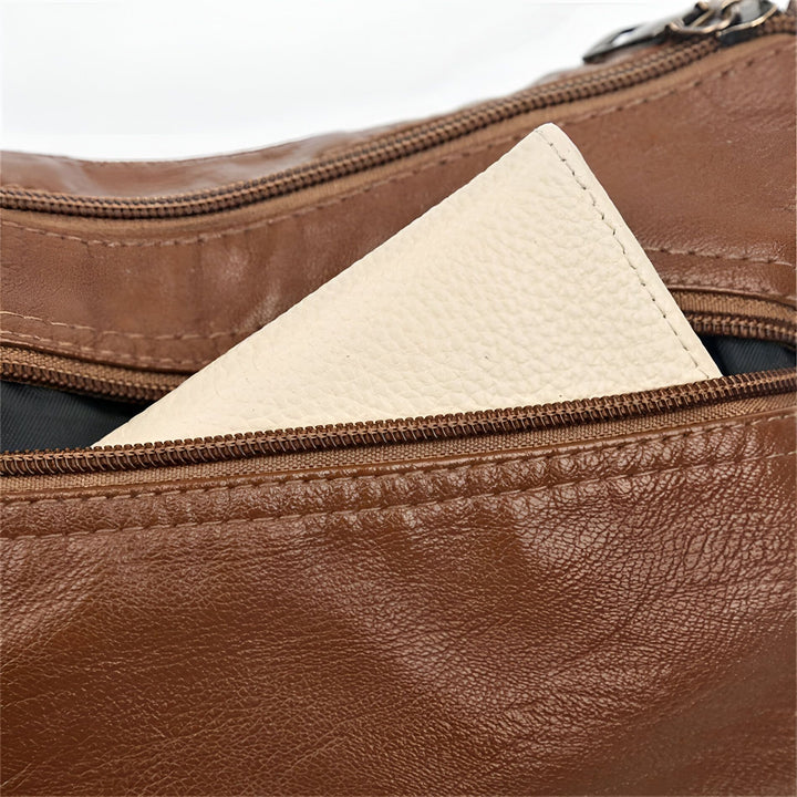 Gros plan d'un objet blanc dans la poche zippée d'un sac en cuir marron., 46194026643680,46194026676448,46194026709216,46194026741984,46194026774752,46194026807520