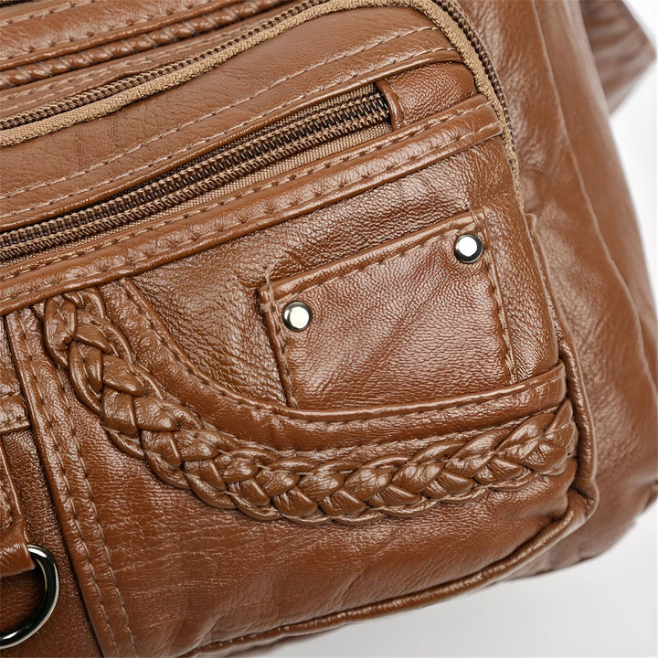 Détail d'un sac en cuir marron avec fermetures éclair, tresse et rivets., 46194026643680,46194026676448,46194026709216,46194026741984,46194026774752,46194026807520