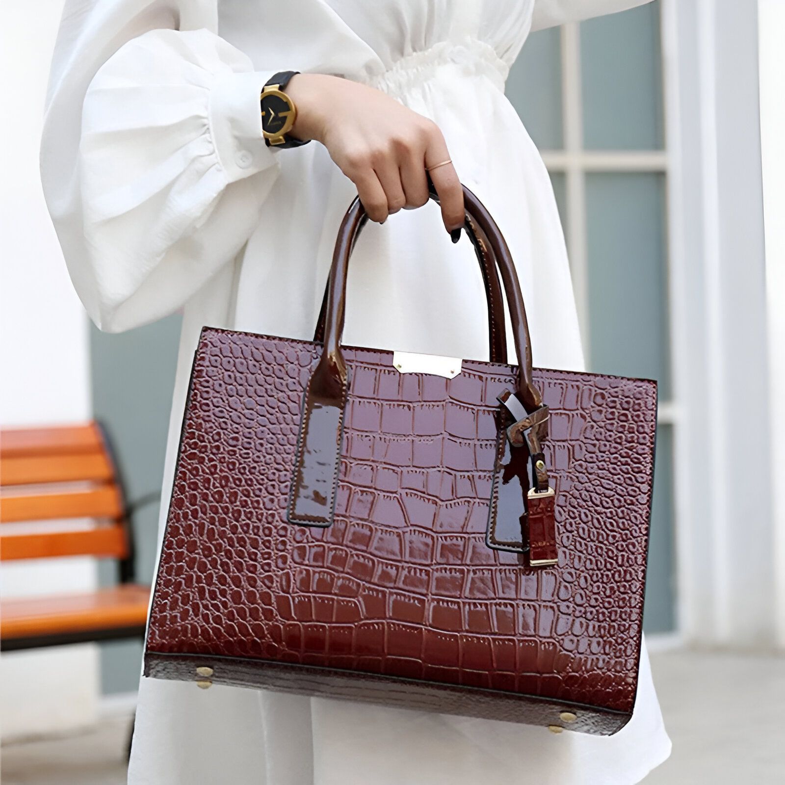 Un sac à main en cuir marron à motif croco porté par une femme.