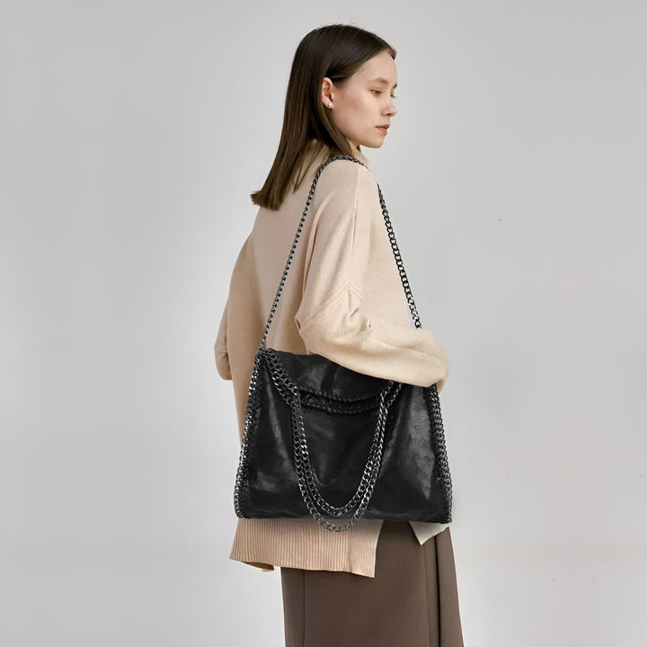 Femme portant un sac noir à chaîne argentée sur l'épaule, vue de dos., 46193949245664,46193949278432,46193949311200