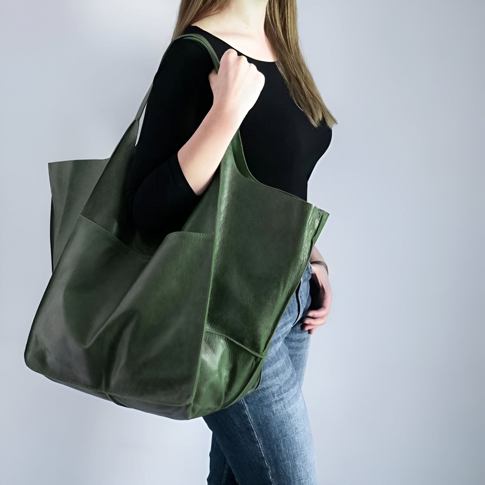 Une femme porte un grand sac à main en cuir vert.