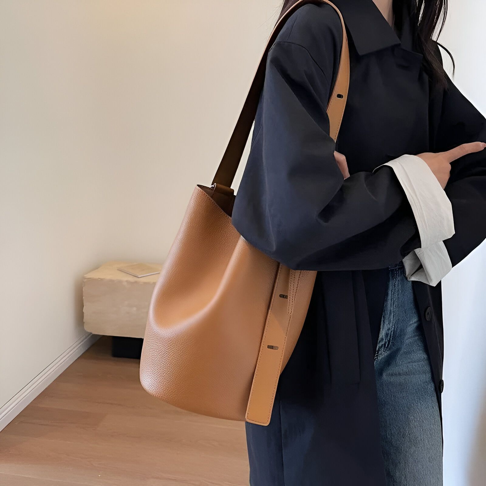 Une femme portant un manteau noir et un sac à main brun clair en cuir.