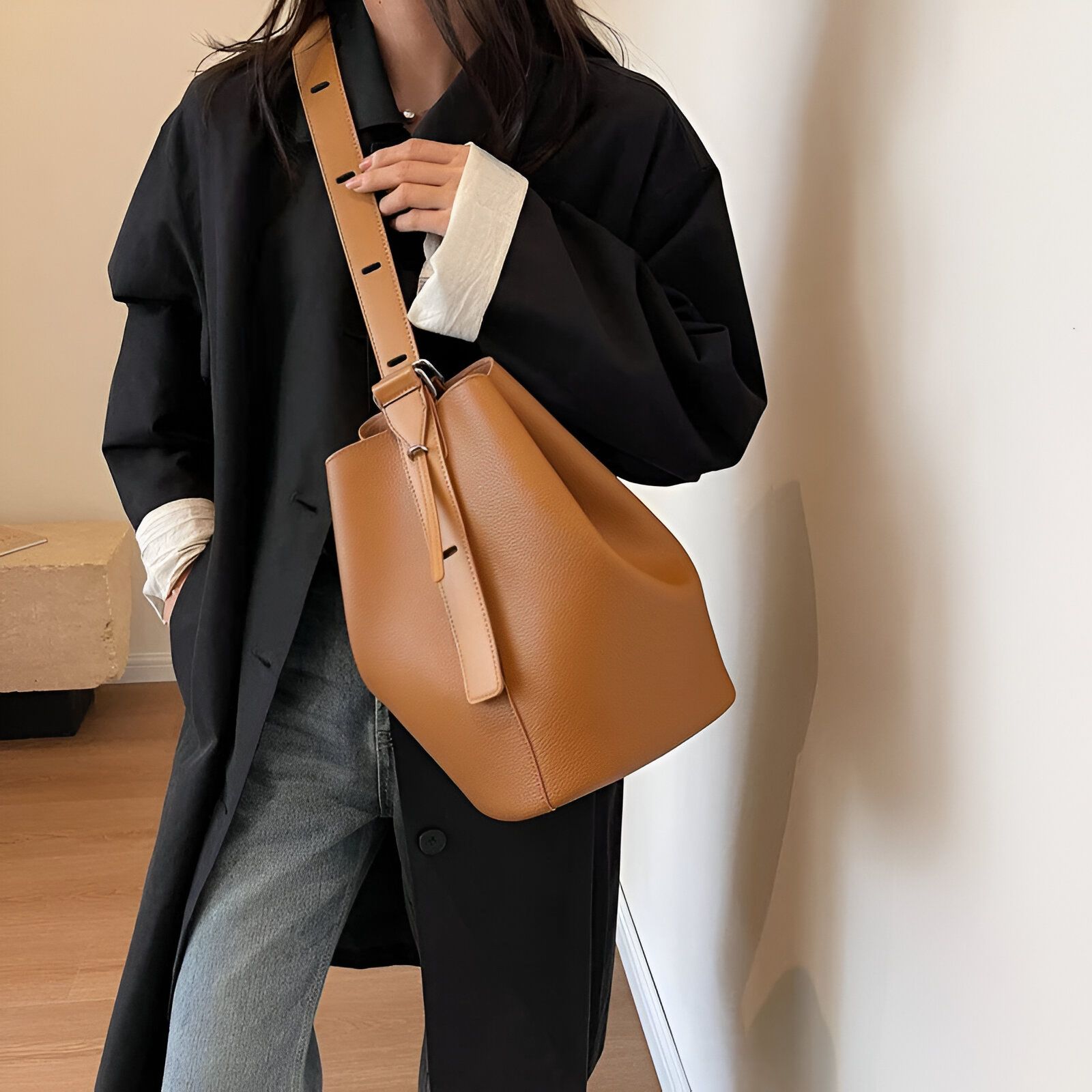 Une femme porte un manteau noir et un sac à main brun.