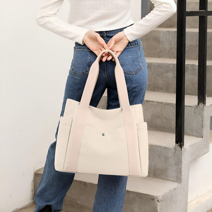 Sac tote bag blanc cassé porté par une personne en jean, près d'un escalier., 46193890590944,46193890623712