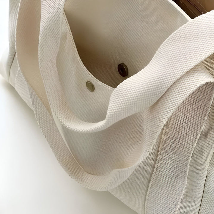 Gros plan sur un sac tote bag en toile beige, montrant la texture et les poignées., 46193890590944,46193890623712