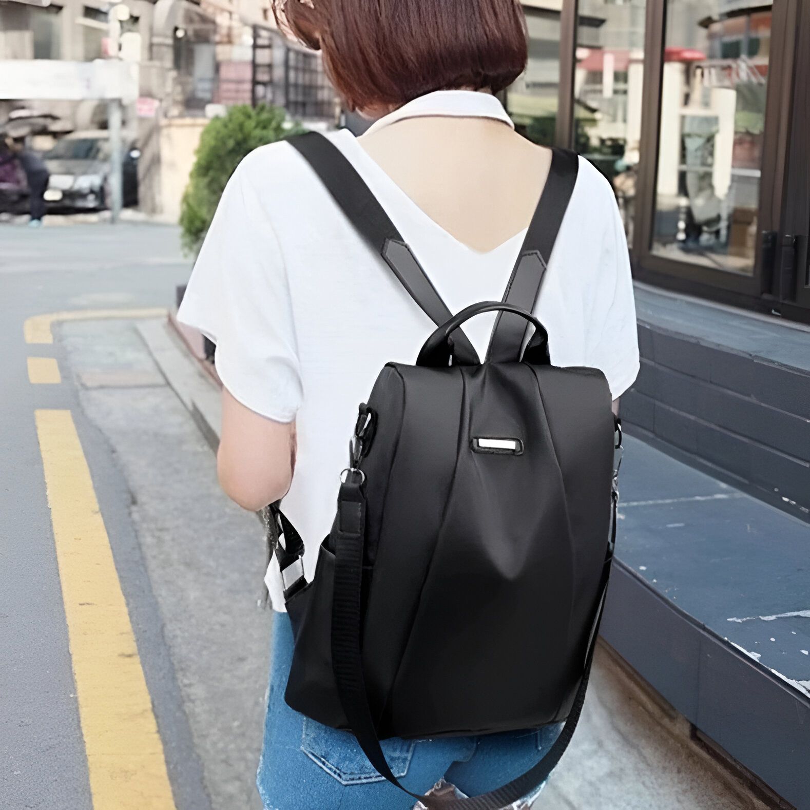 Une femme portant un sac à dos noir élégant. Le sac a des bretelles réglables et est parfait pour les voyages ou la vie quotidienne.