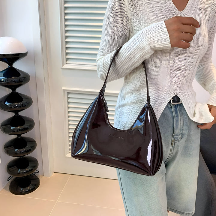 Sac à bandoulière bordeaux brillant porté par une personne en pull blanc et jean., 46193869619424,46193869652192,46193869684960,46193869717728,46193869750496