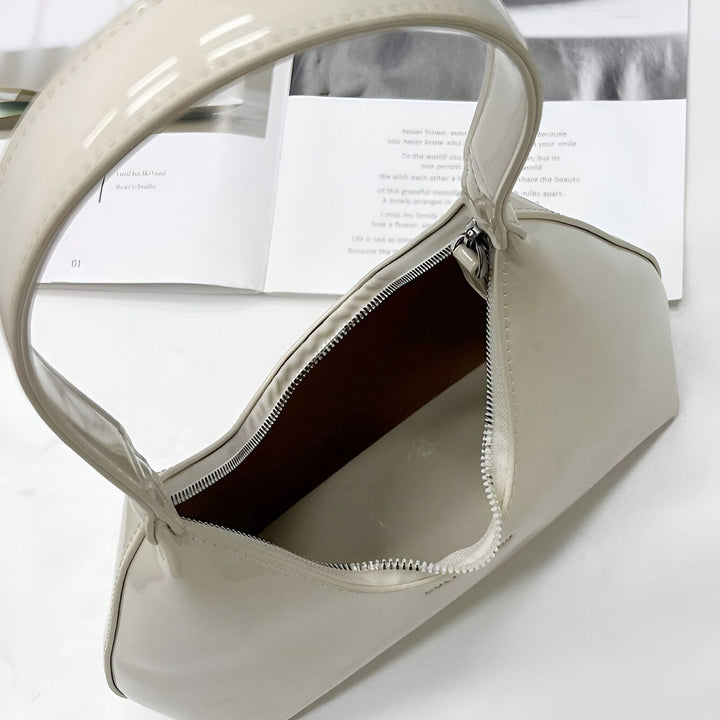 Sac à épaule beige clair verni ouvert sur une table., 46193869619424,46193869652192,46193869684960,46193869717728,46193869750496