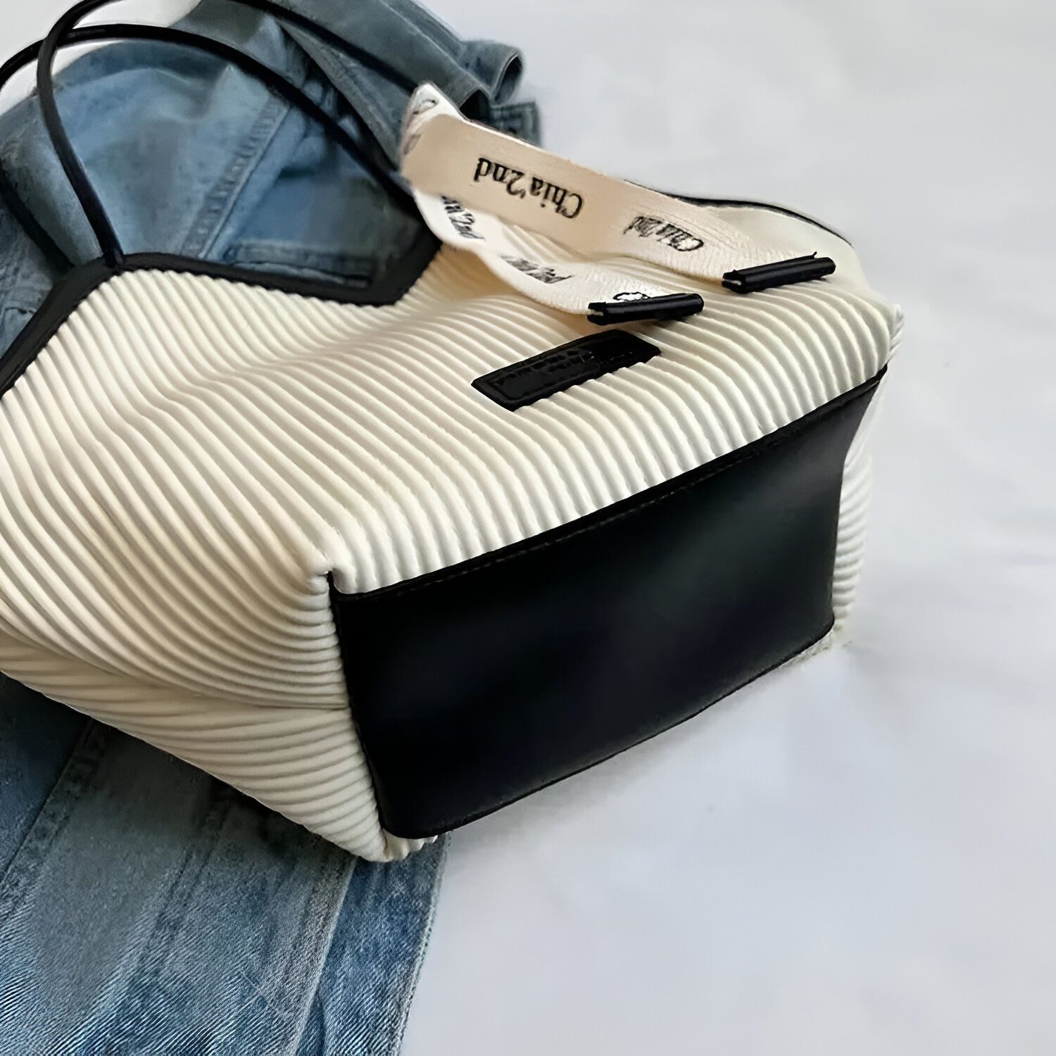 Un sac à main blanc rayé avec une poche en cuir noir.