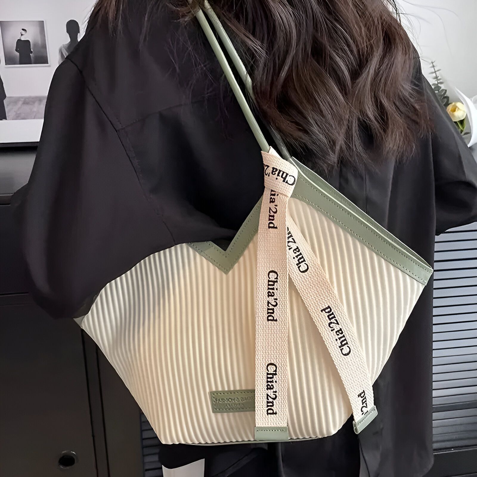 Une femme portant un sac à main en toile rayée beige avec une bordure verte et des lanières vertes avec le logo "Chia 2nd" écrit dessus.