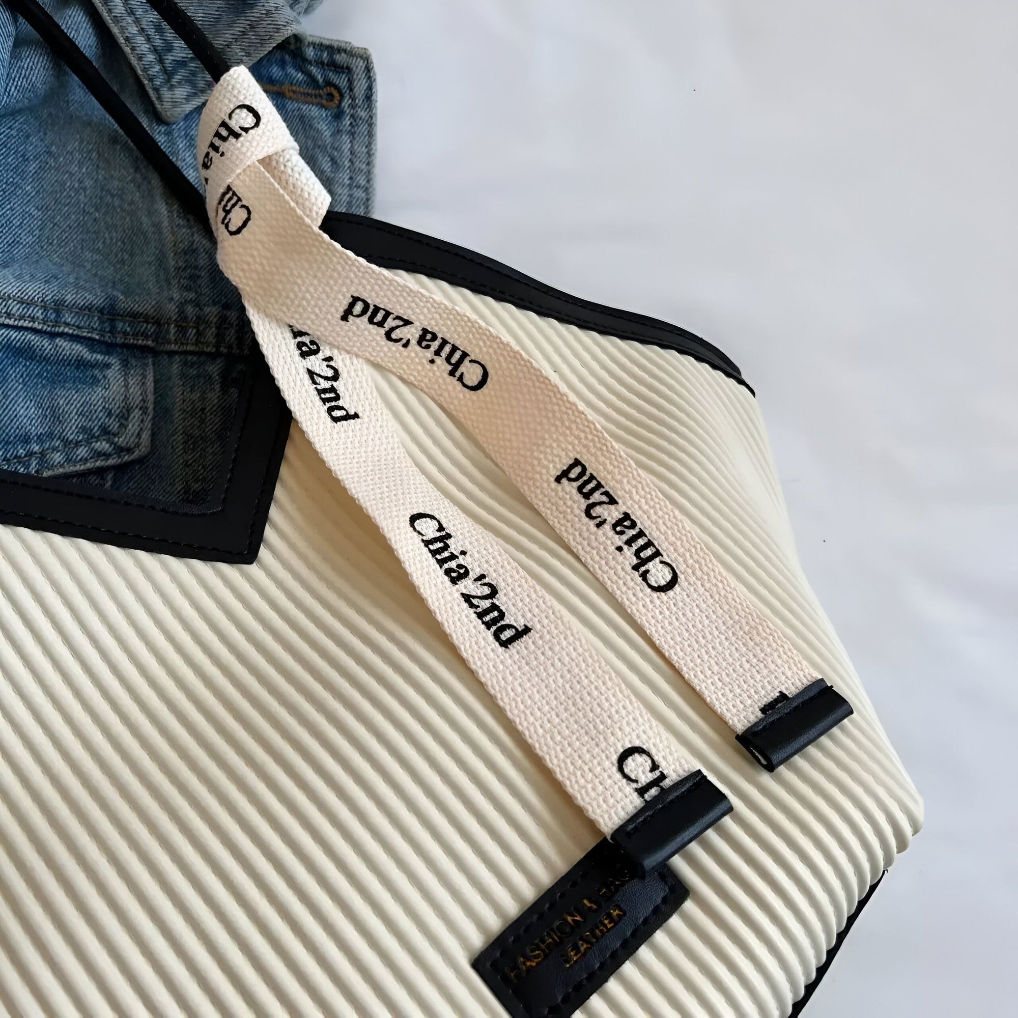 Un sac à main en crème avec des détails noirs et des sangles en coton blanc avec l'inscription "Chia 2nd".